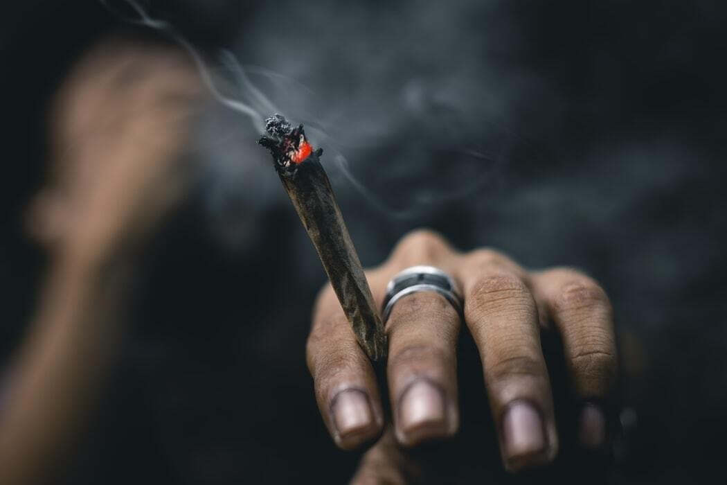 cannabis smoker holding alight joint